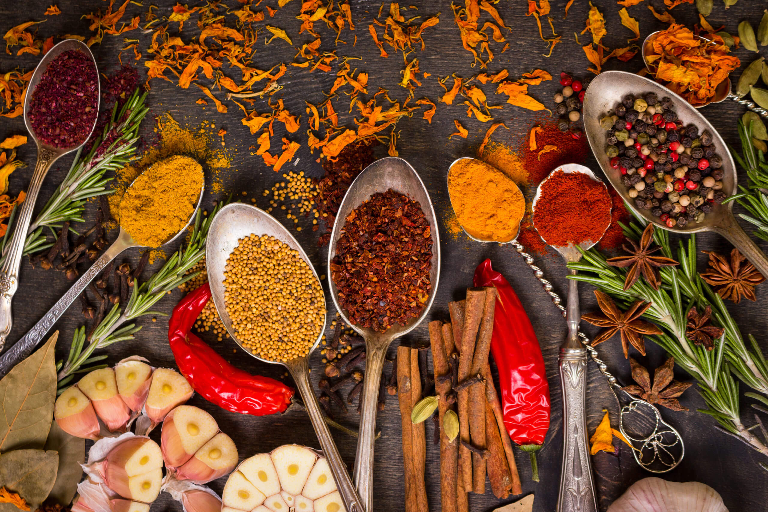 Set of various aromatic colorful spices in old vintage spoons and herbs on a dark wooden background. Ingredients for cooking. Top view